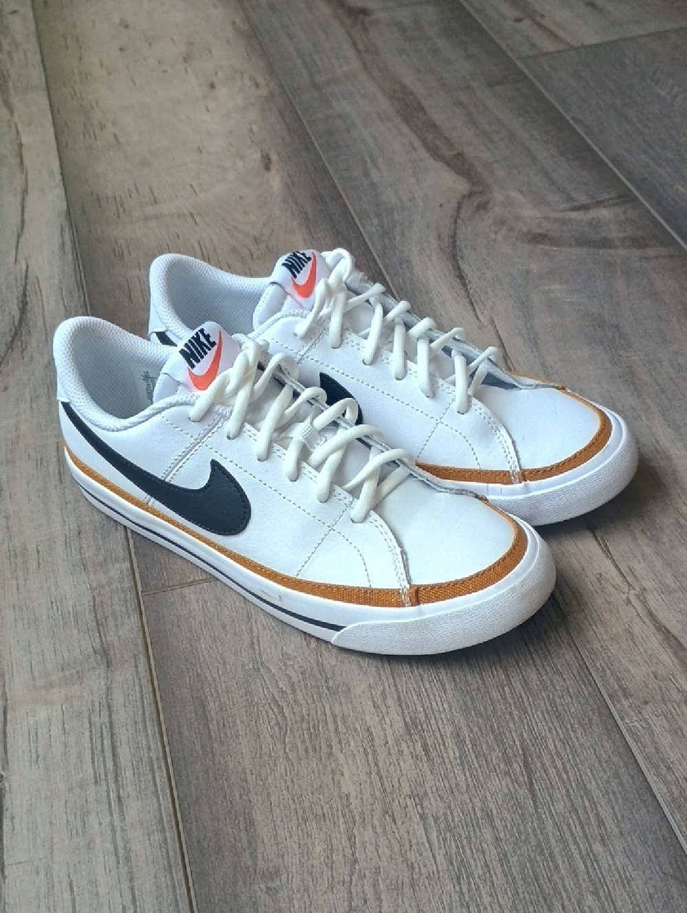 Nike White Low-Top Sneakers with Black Swoosh and Gold Accent